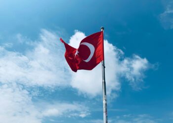 Masmavi gökyüzü ve bulutlar önünde dalgalanan kırmızı renkli Türk bayrağı.