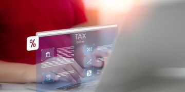 Bilgisayar başında klavye kullanan kişinin üzerinde online vergi arayüzü görünmektedir.