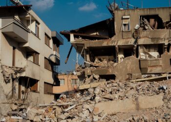 Depremde yıkılmış binalar ve enkaz yığını altında kalan sokak görünümü.