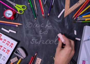 Tahta kara tahta üzerinde tebeşirle back to school yazısı ve okul malzemeleri.