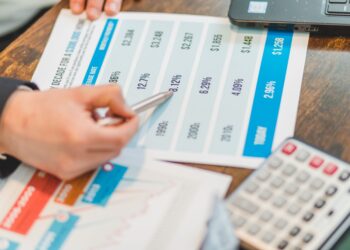 Masada finansal grafikler ve faiz oranlarını gösteren tabloları inceleyen bir kişi.