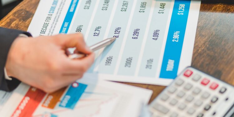 Masada finansal grafikler ve faiz oranlarını gösteren tabloları inceleyen bir kişi.