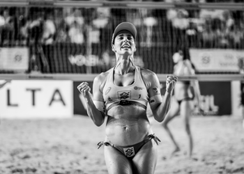 Siyah beyaz fotoğrafta zaferini kutlayan kadın voleybolcu.