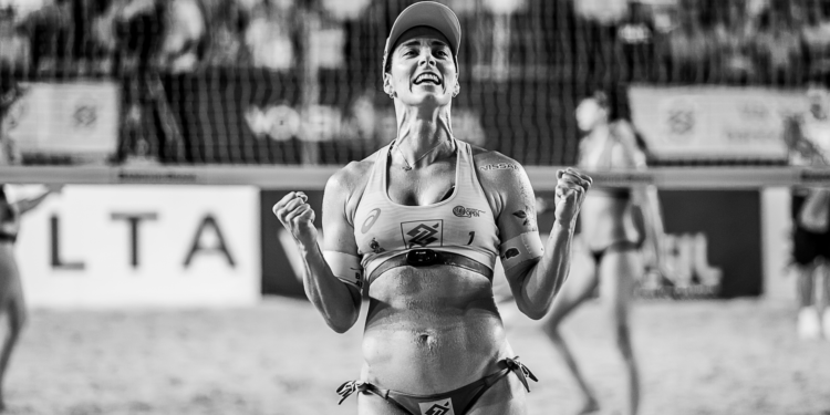 Siyah beyaz fotoğrafta zaferini kutlayan kadın voleybolcu.