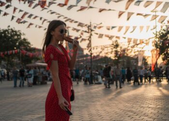 Kırmızı elbiseli bir kadın İstanbul silueti önünde sokakta simit yiyor.
