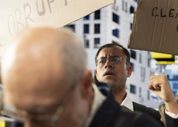 Protesto yürüyüşünde pankart taşıyan ve tepki gösteren öfkeli kalabalık.