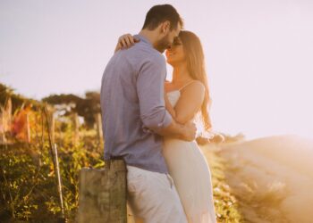 Gün batımında birbirine sarılan ve gülümseyen romantik genç bir çift.