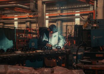 Fabrikada koruyucu maske takarak kaynak yapan bir işçi.