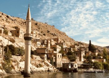 Tarihi taş evler ve gövdesinin bir kısmı suya batmış minare.