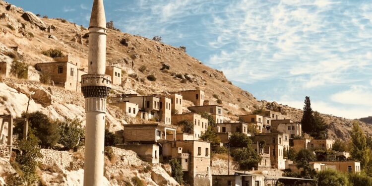 Tarihi taş evler ve gövdesinin bir kısmı suya batmış minare.
