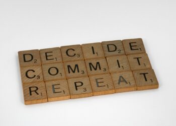 Üzerinde DECIDE, COMMIT ve REPEAT yazan ahşap harf karoları yerleştirilmiş.