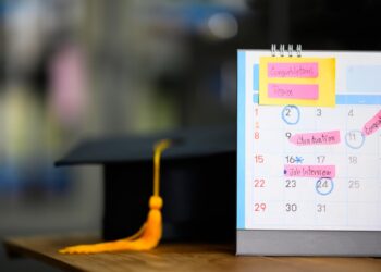Mezuniyet kepi ve üzerinde notlar ile tarihler bulunan masa takvimi.