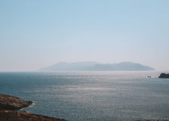 Açık mavi gökyüzü altında sakin ve dalgalı deniz üzerindeki Ege adaları.