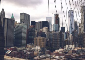 New York şehrinin gökdelenleri ve köprü tellerinin arkasındaki manzarası.